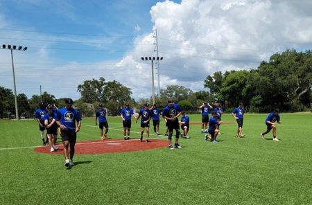 Players wearing blue uniforms run on the field during practice